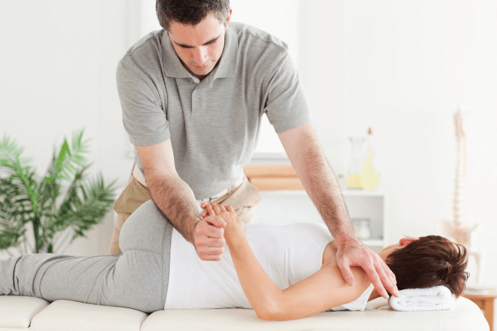 Physiotherapist twisting the body of a lady