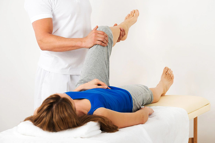 Woman wearing a blue Tshirt receiving a Physiotherapy treatment for her leg